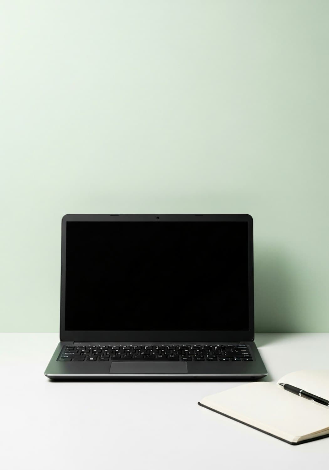 Laptop und aufgeschlagenes Notizbuch auf hellem Schreibtisch
